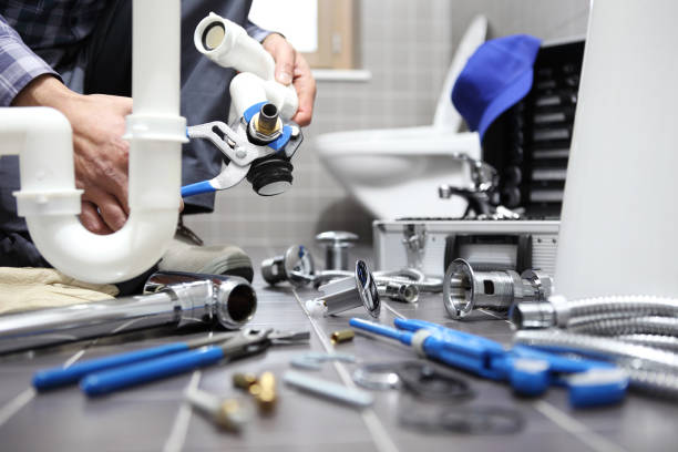 Plumber assembling a sink drain with plumbing tools and fittings nearby